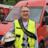 Ein Mann steht vor einem Feuerwehrwagen.