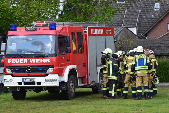 Feuerwehrleute stehen am Mannschaftswagen.