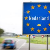 Ein Auto fährt an einem Schild mit der Aufschrift „Nederland“ vorbei, das an der Grenze zwischen den Niederlanden und Deutschland steht.