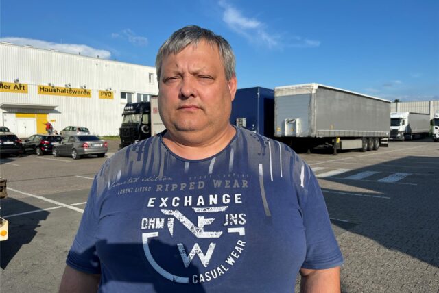 Lkw-Fahrer Michail (Name geändert) steht auf einem Parkplatz in Holzwickede vor anderen Lastwagen.