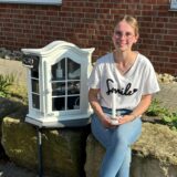 Lisa E. sitzt neben ihrem neuen Selbstbedienungsschrank mit Dekoartikeln
