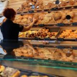 Eine Verkäuferin greift in einer Bäckerei ein Brot aus der Auslage.