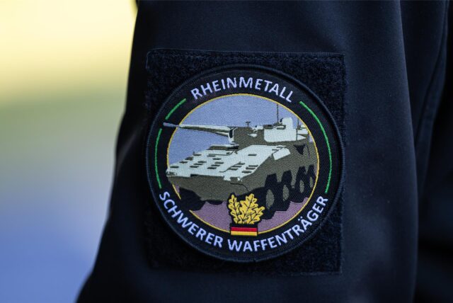 „Rheinmetall, Schwerer Waffenträger“ steht auf dem Abzeichen eines Mitarbeiters.