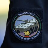 „Rheinmetall, Schwerer Waffenträger“ steht auf dem Abzeichen eines Mitarbeiters.
