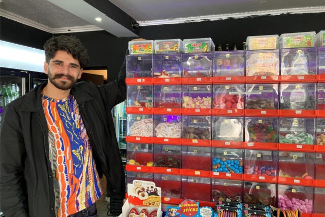 Sores Ekinci steht in seinem Vintage Kiosk in der Altstadt von Recklinghausen neben Schubfächern, in denen verschiedene Weingummi-Sorten liegen.