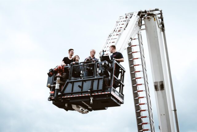 In einem Krankorb der Werkfeuerwehr stehen vier Personen.