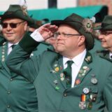 Die Montage zweier Bild zeigt einen Mann in einem weißen Hemd und zwei salutierende Schützen