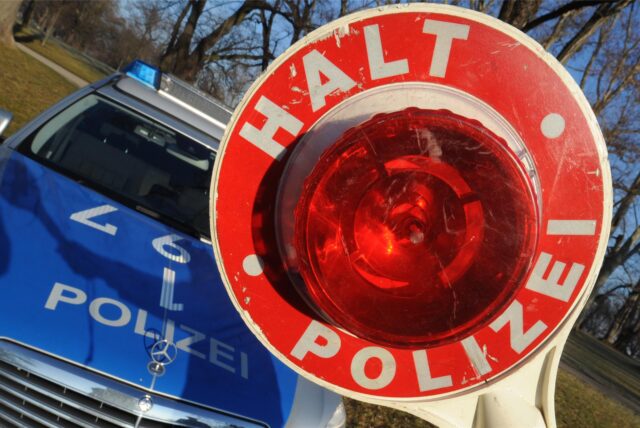Symbolbild zeigt eine Polizeikelle vor einem Polizeiauto.