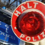 Symbolbild zeigt eine Polizeikelle vor einem Polizeiauto.