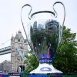 Zu sehen ist der Pokal der Champions League neben einem angeklebten Zettel, auf dem geänderte Öffnungszeiten stehen.
