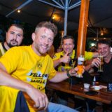 Vier Männer mit BVB-Trikots sitzen an einem Biergarten-Tisch und trinken Bier.
