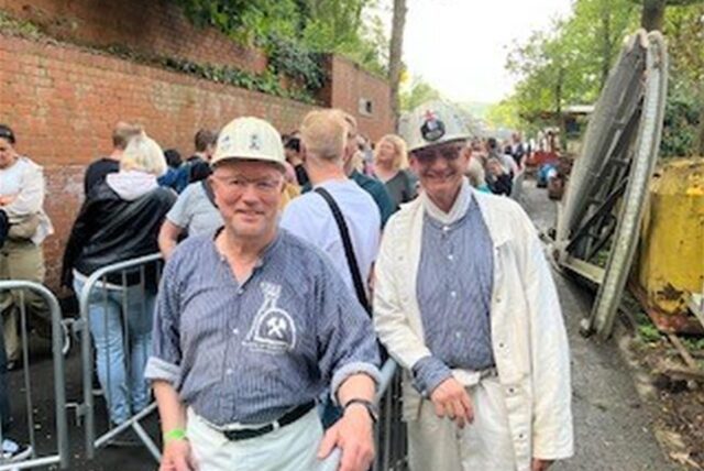 Zwei Bergleute in traditioneller Kluft mit Helm stehen auf dem Gelände des Trainingsbergwerks in Recklinghausen.