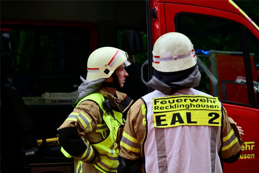 Zwei Feuerwehrmänner aus Recklinghausen stehen vor einem Einsatzfahrzeug.