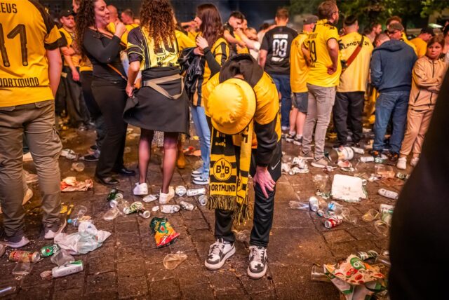 Eine Menge an BVB-Fans stehen am 01. Juni auf dem Hansaplatz in Dortmund. Auf dem Boden liegt jede Menge Müll.