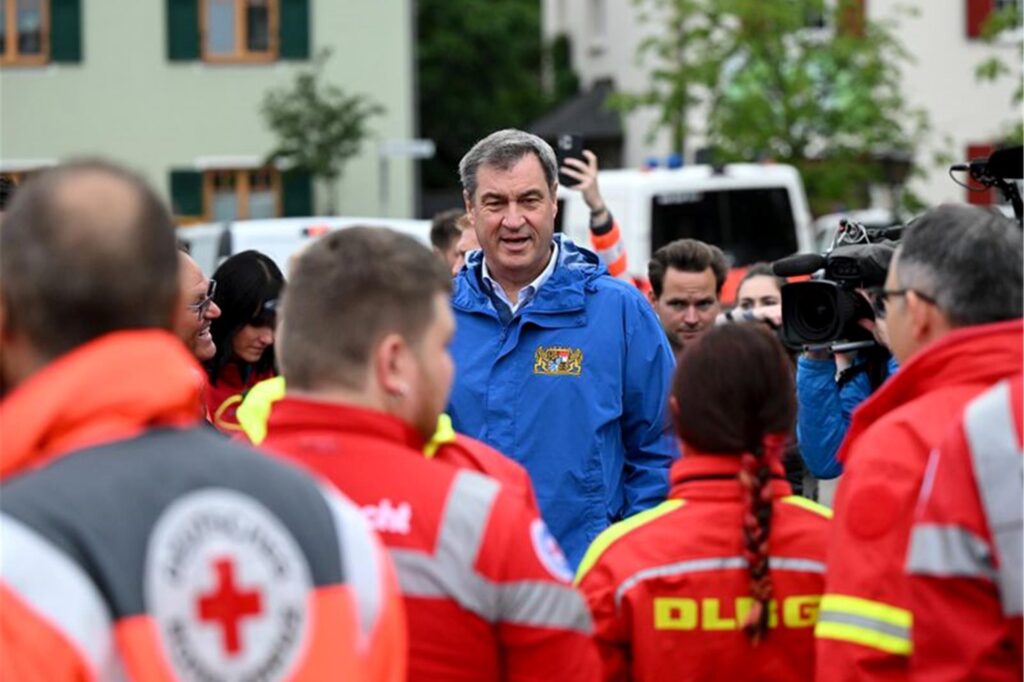 Bayerns Ministerpräsident Markus Söder (M, CSU), spricht zu Einsatzkräften vom Roten Kreuz, DLRG und anderen Rettungskräften bei einer Ortsbesichtigung im vom Hochwasser betroffenen oberbayerischen Reichertshofen.