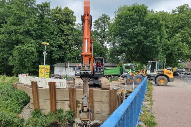 Ein Bagger arbeitet an einem Brückengeländer.