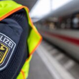 Ein Polizist steht an einem Bahnsteig. Im Hintergrund ist unscharf ein ICE zu erkennen.