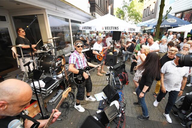 Die Musikgruppe The Servants während eines Auftritts in der Antoniusstraße, auf der viele Menschen sind, in Herten.