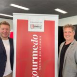 Sebastian Schalk und Daniel Östreich stehen neben einem Gourmedo-Plakat.