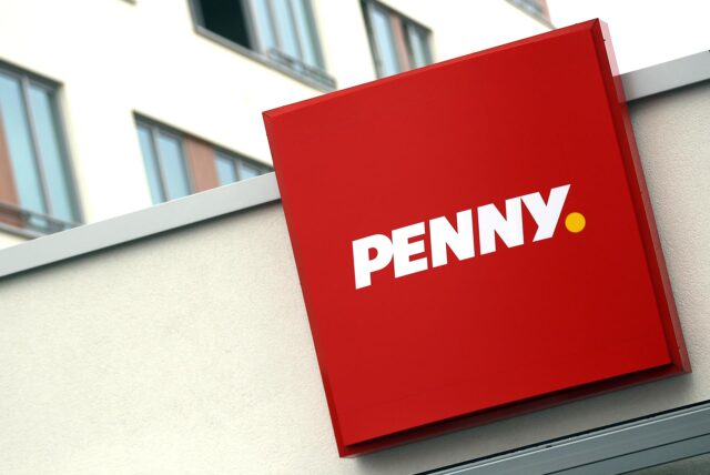 An einer Penny-Filiale hängt ein großes Schild mit dem Logo des Discounters.