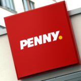 An einer Penny-Filiale hängt ein großes Schild mit dem Logo des Discounters.