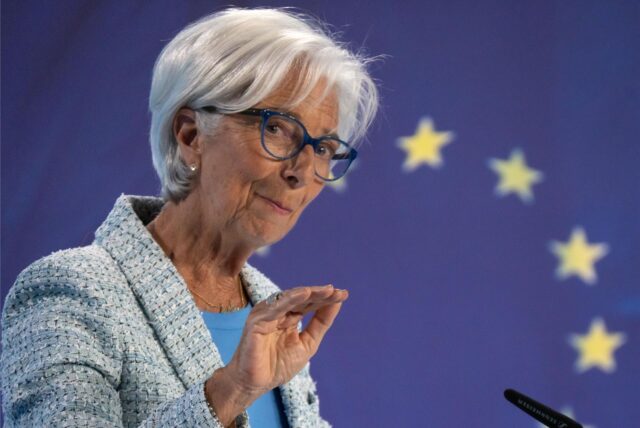 Die EZB-Chefin Christine Lagarde gestikuliert leicht mit ihrer Hand und erklärt auf einem Podium vor Journalisten ihre Entscheidung.