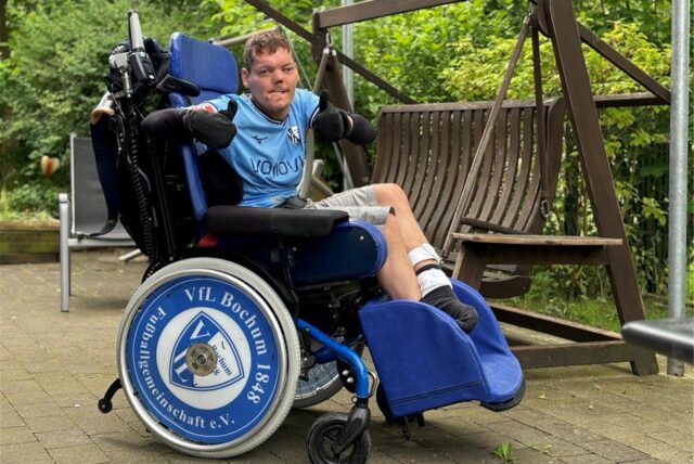 Ein Mann sitzt in einem Rollstuhl und reckt beide Daumen nach oben. Er trägt ein Bochum-Trikot und auch die Rollen seines Stuhls ziert das Logo des Vereins.