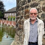 Älterer Mann steht vor dem Siebenteufelsturm.