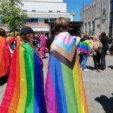 Zwei Jugendliche tragen eine Regenbogenflagge.