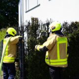 Feuerwehrleute beim Löschen vor iener verbrannten Hecke an ienem Wohnhaus im Hasenbkamp in Castrop-Rauxel.