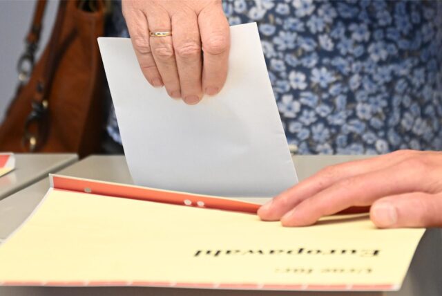 Ein Stimmzettel wird in eine Wahlurne gesteckt.