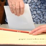 Ein Stimmzettel wird in eine Wahlurne gesteckt.