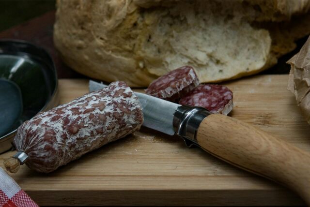 Salami wird mit einem Messer geschnitten.