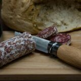 Salami wird mit einem Messer geschnitten.