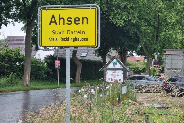 Ein Ortseingangsschild an einer Straße.