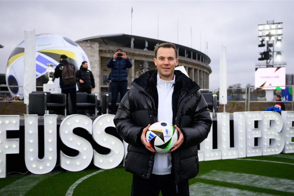 Nationaltorwart Manuel Neuer steht vor einem Schriftzug 