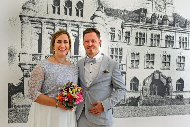Das Brautpaar Mirja Riewe und Matthias Melaloli vor einer Abbildung des Recklinghäuser Rathauses