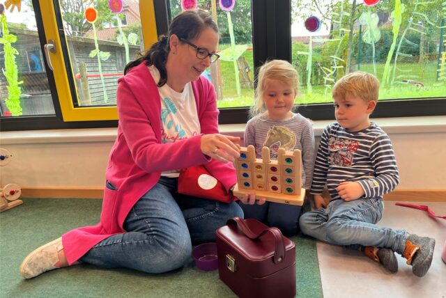 Steffi Kopper spielt auf dem Boden mit zwei Kindern.