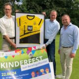 Dr. Johannes und Georg Brauckmann-Berger sowie Maximilian Knebel (von links) halten einen großen Bilderrahmen mit einem signierten Trikot von Borussia Dortmund in den Händen.