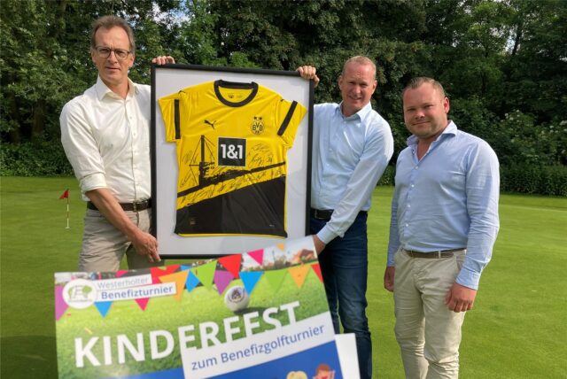 Dr. Johannes und Georg Brauckmann-Berger sowie Maximilian Knebel (von links) halten einen großen Bilderrahmen mit einem signierten Trikot von Borussia Dortmund in den Händen.