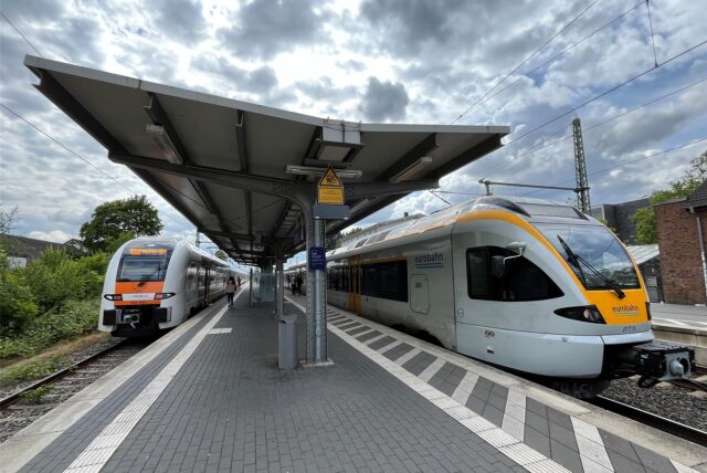 Das Gleis eines Bahnhofs ist zu sehen. Auf den Gleisen stehen Züge.