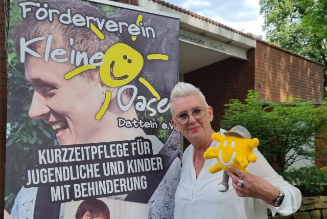 Ein Frau steht vor einem Plakat.