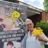 Ein Frau steht vor einem Plakat.