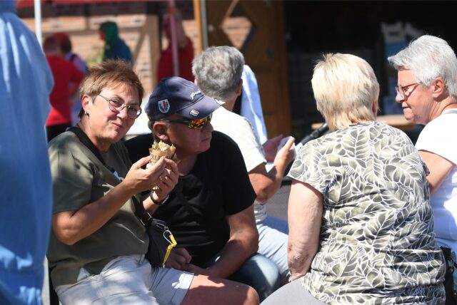 Gäste sitzen in der Sonne und unterhalten sich während des Picknicks am Hof Emscher-Auen in Castrop-Rauxel.