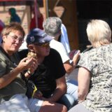 Gäste sitzen in der Sonne und unterhalten sich während des Picknicks am Hof Emscher-Auen in Castrop-Rauxel.