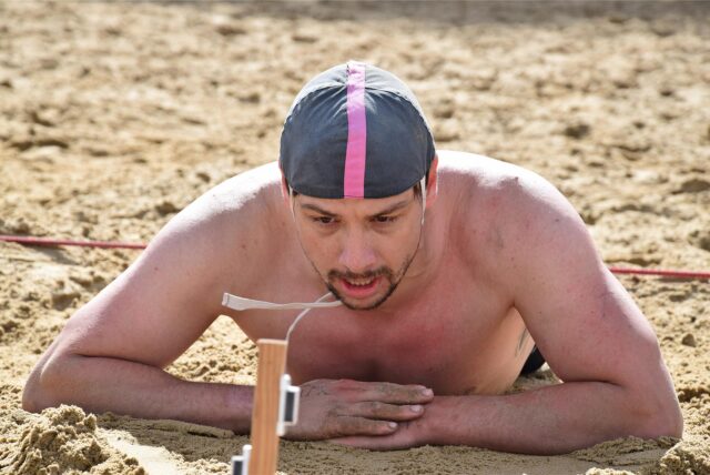 Mann liegt erschöpft im Sand