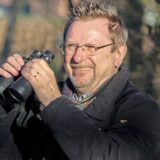 Eine Fotomontage zeigt zur Hälfte eine Blindschleiche, dieses Tier sieht einer Schlange sehr ähnlich. Die andere Hälfte zeigt einen Mann mit Fernglas, der fröhlich lächelt.