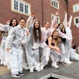 Eine Gruppe Jugendlicher steht in weißen Maleranzügen auf dem Schulhof des städtischen Gymnasiums und feiern ausgelassen.