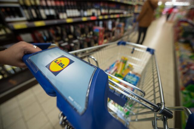Ein gefüllter Einkaufswagen steht im Gang im Supermarkt.