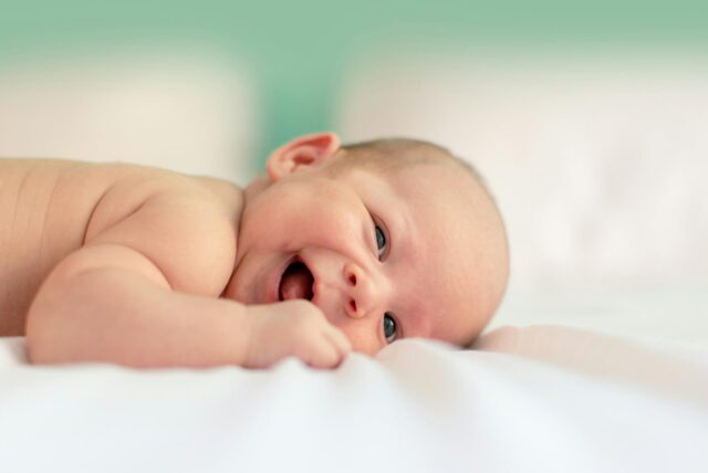 Ein Baby schaut lachend in die Kamera.